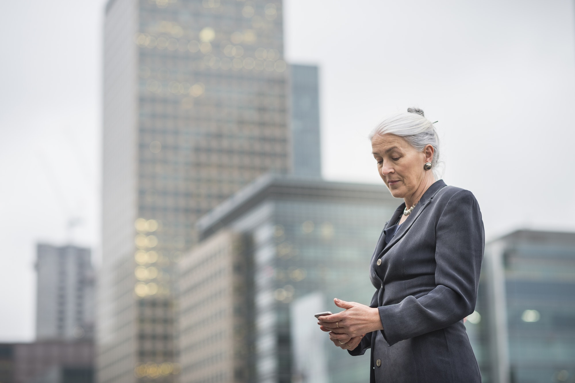 Businesswoman using mobile phone, Canary Wharf, London, UK